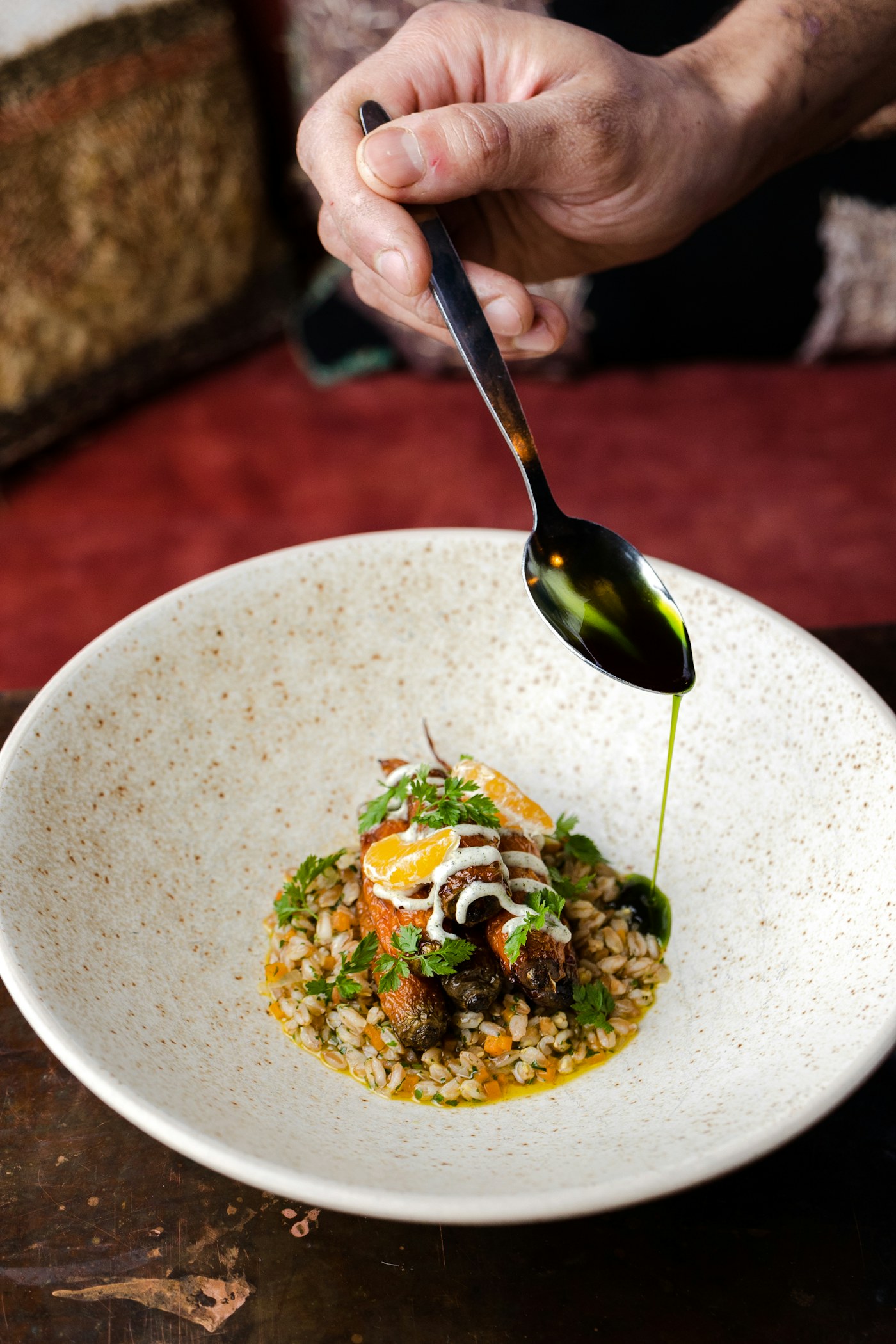 Seasonal vegetable dish being finished with herb oil